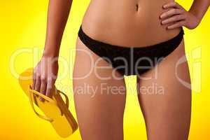 Part of female body wearing black bikini  and holding yellow fli