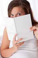 Woman peeking over white book