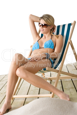 Beach - Young woman in bikini sitting on deck chair