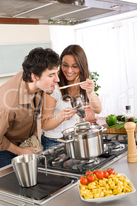 Couple cook in kitchen - man taste food
