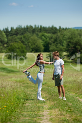 Young man and woman exercising in spring meadow