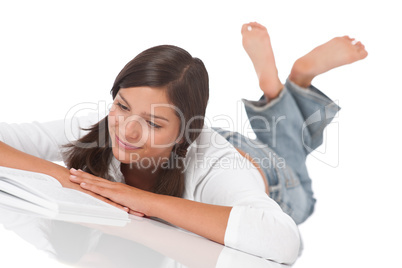 Smiling teenager lying down and reading book