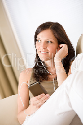 Woman holding music player listening on sofa home