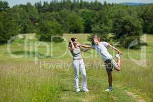 Young man and woman exercising in spring meadow