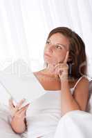 Woman thinking while reading book