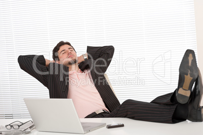 Successful businessman in black suit relaxing at office