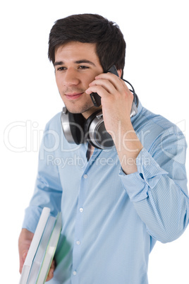 Male student calling with mobile phone holding books