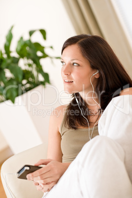 Woman holding music player listening in lounge