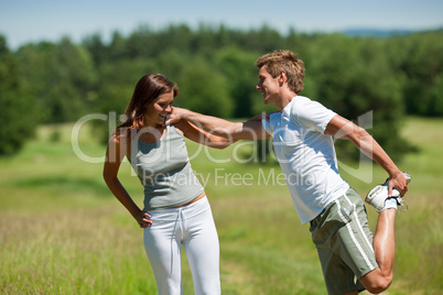 Young man and woman exercising in spring meadow