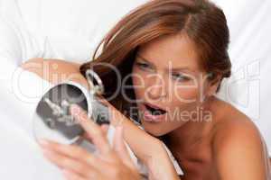 White lounge - Brown hair woman yawning and holding alarm clock