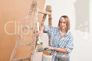 Home improvement: Smiling woman with paint and brush painting wa
