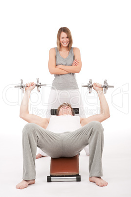 Fitness - young man exercising on bench with weights