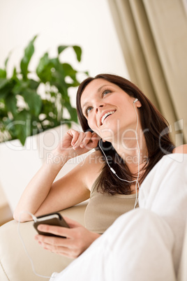 Woman holding music player listening in lounge