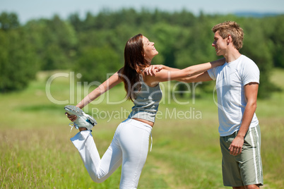 Young man and woman exercising in spring meadow