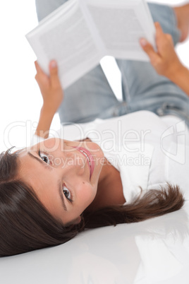 Smiling teenager lying down and reading book