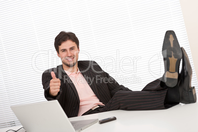 Successful businessman gesturing at office, thumbs-up