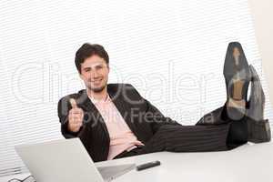 Successful businessman gesturing at office, thumbs-up