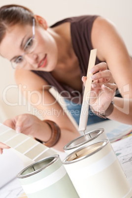 Female designer with can of paint choosing color