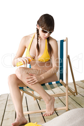 Beach - woman in bikini apply suntan lotion