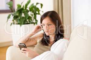 Woman holding music player listening with earbuds home