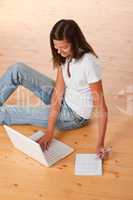 Smiling teenager sitting with laptop and writing notes