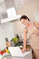 Cheerful woman with laptop in the kitchen