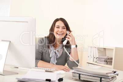 Smiling young woman on the phone at office