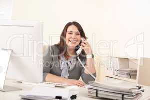 Smiling young woman on the phone at office