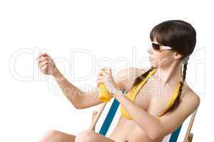 Beach - woman in bikini apply suntan lotion