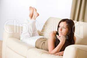 Young happy woman relax lying down on sofa