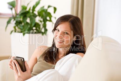 Woman holding music player listening in lounge