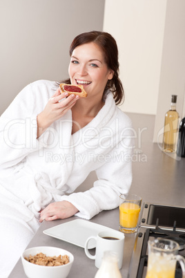 Young woman eating toast for breakfast in kitchen