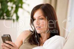 Woman holding music player listening with earbuds home