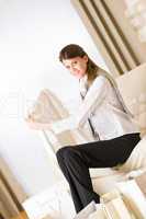 Young business woman sitting on sofa with shopping bag