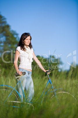 Woman with old-fashioned bike in summer meadow