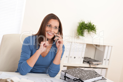 Smiling female architect holding phone and pen