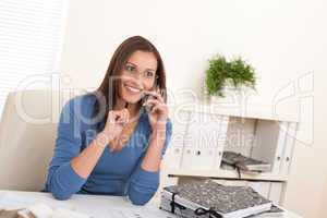 Smiling female architect holding phone and pen