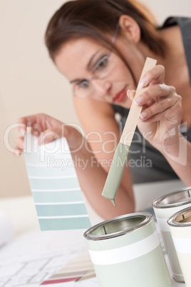 Female designer with can of paint choosing color