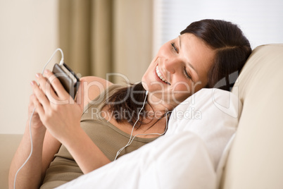 Woman holding music player listening with earbuds home