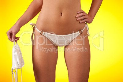 Part of female body wearing white bikini   holding bra