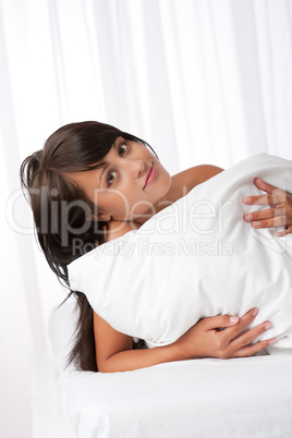 Beautiful young woman lying in white bed