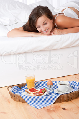Smiling woman in bed watching homemade breakfast