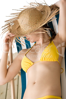 Beach - woman with straw hat in yellow bikini sunbath