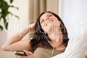 Woman holding music player listening in lounge