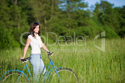 Woman with old-fashioned bike in summer meadow