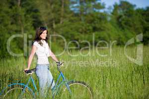 Woman with old-fashioned bike in summer meadow