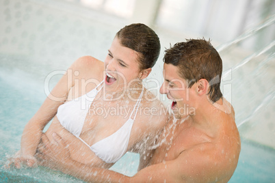Swimming pool - young couple have fun under water stream