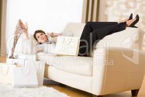 Young business woman lying down on sofa with shopping bag