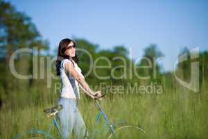 Woman with old-fashioned bike in summer meadow