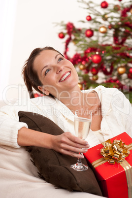 Smiling woman with Christmas present and glass of champagne